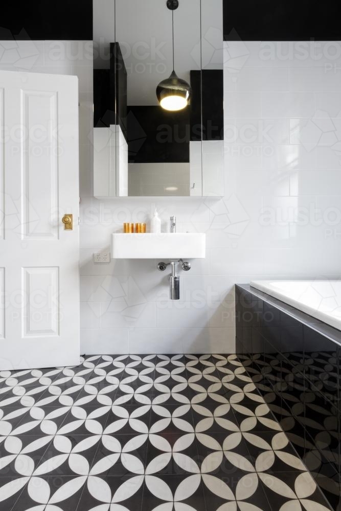 Moroccan styled monochrome bathroom with patterned floor tiles and wall hung vanity - Australian Stock Image