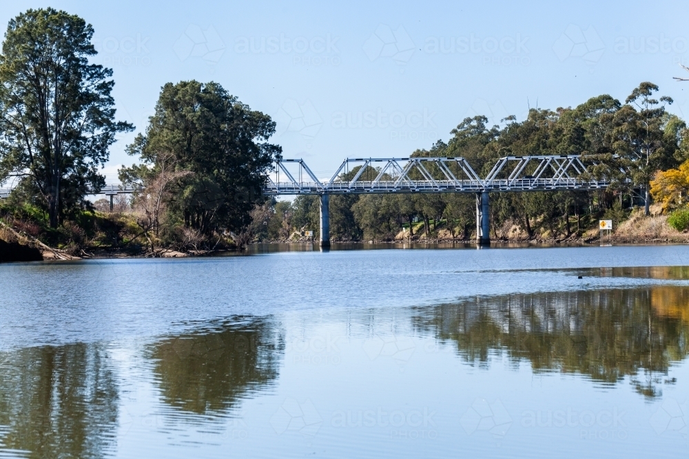Morpeth bridge seen from along river on sunlit day - Australian Stock Image