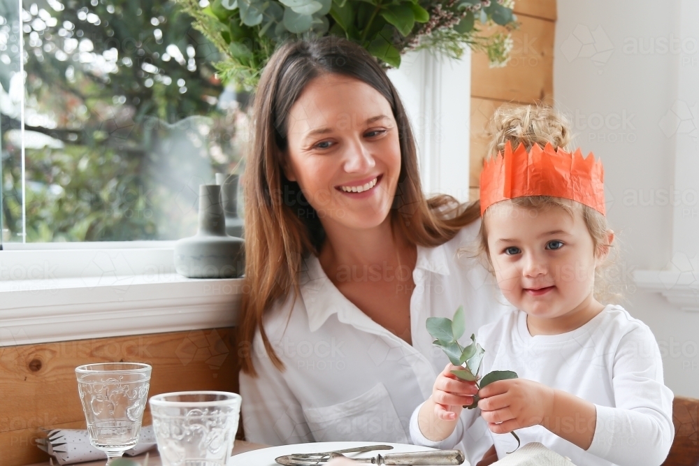 Mother and daughter at table smiling - Australian Stock Image
