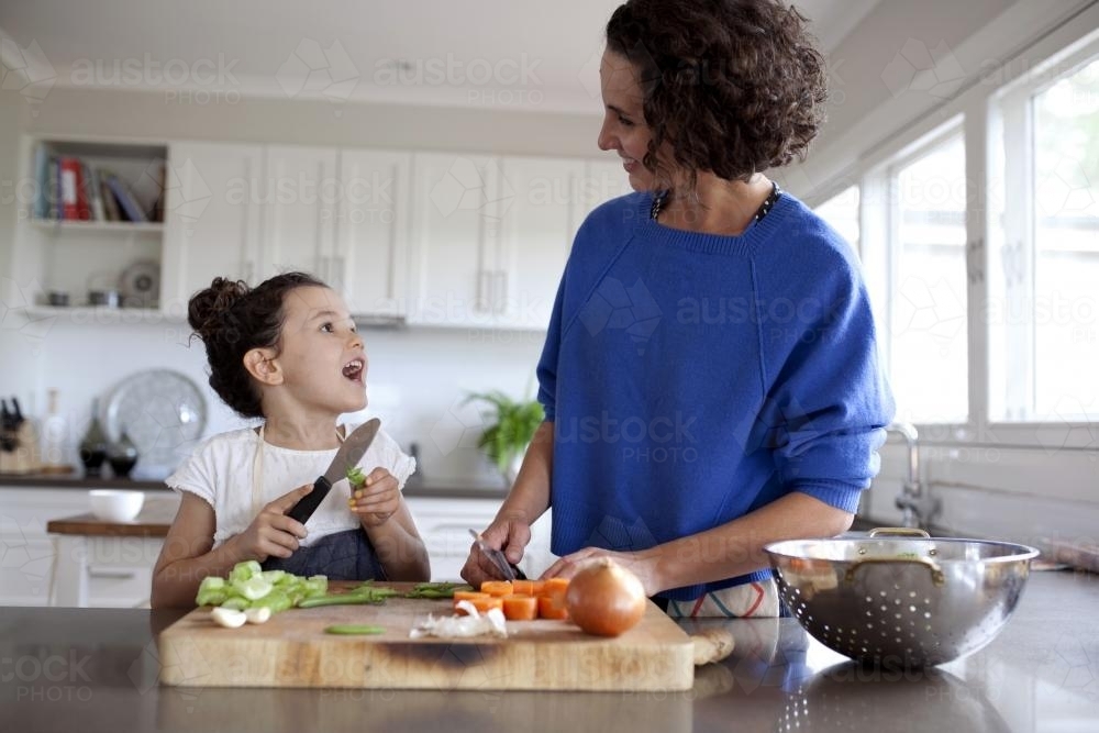 Mother and daughter chopping vegetables in kitchen - Australian Stock Image