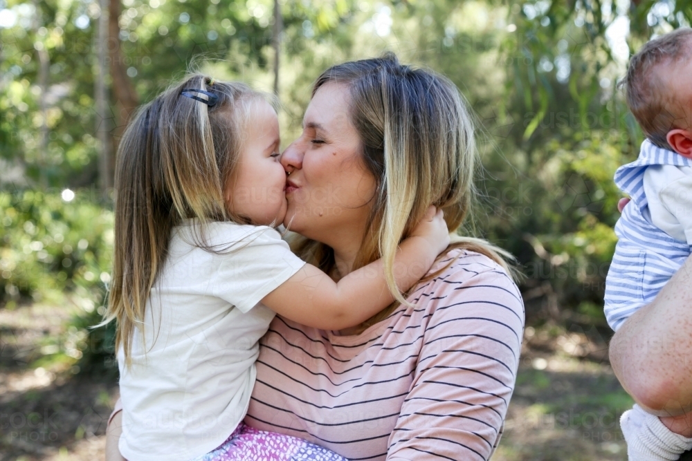 Mother and daughter cuddling and kissing - Australian Stock Image