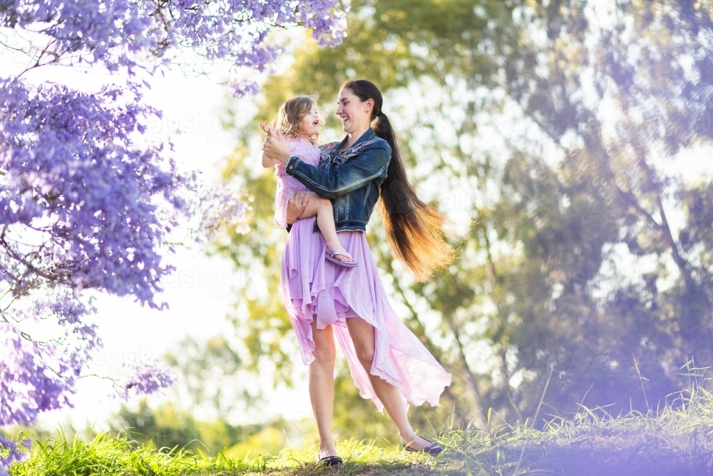 Mother and daughter dancing outside on hilltop with daughter in arms - Australian Stock Image