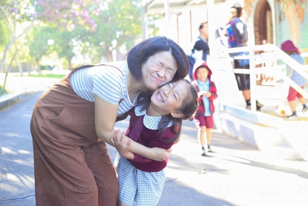 Mother and daughter hugging and smiling at school - Australian Stock Image