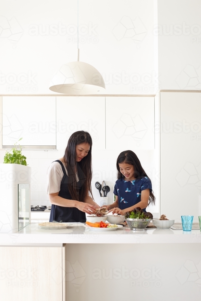 Mother and daughter in kitchen cooking together - Australian Stock Image