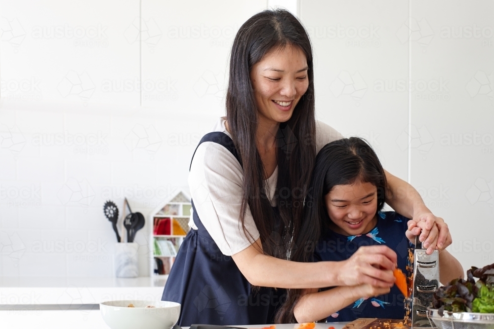 Mother and daughter in kitchen cooking together - Australian Stock Image