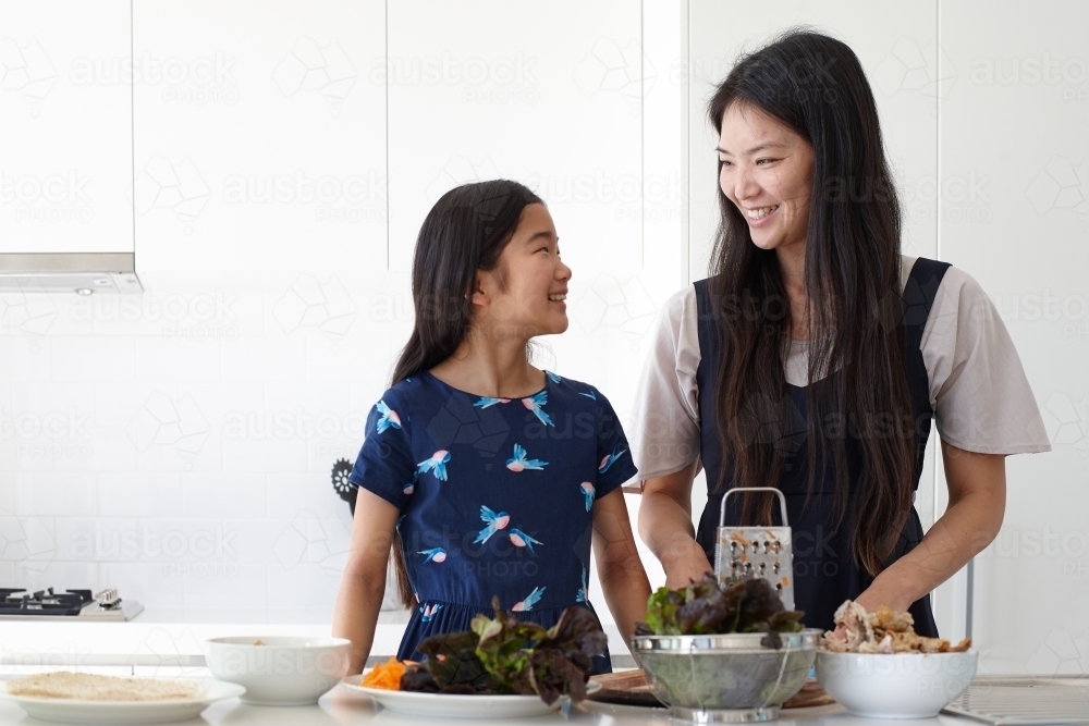 Mother and daughter in kitchen cooking together - Australian Stock Image