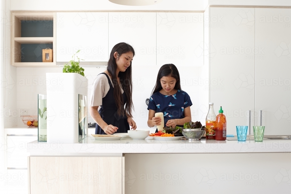 Mother and daughter in kitchen cooking together - Australian Stock Image