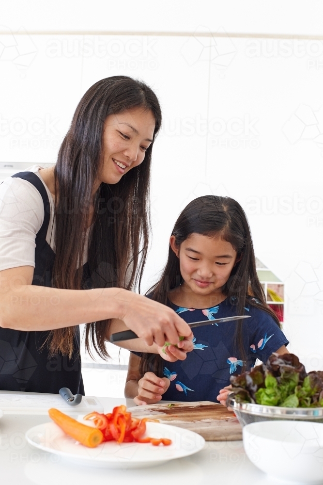 Mother and daughter in kitchen together preparing healthy lunch - Australian Stock Image