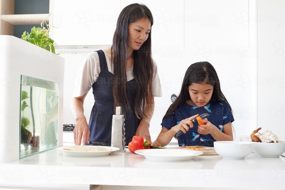 Mother and daughter in kitchen together preparing lunch - Australian Stock Image