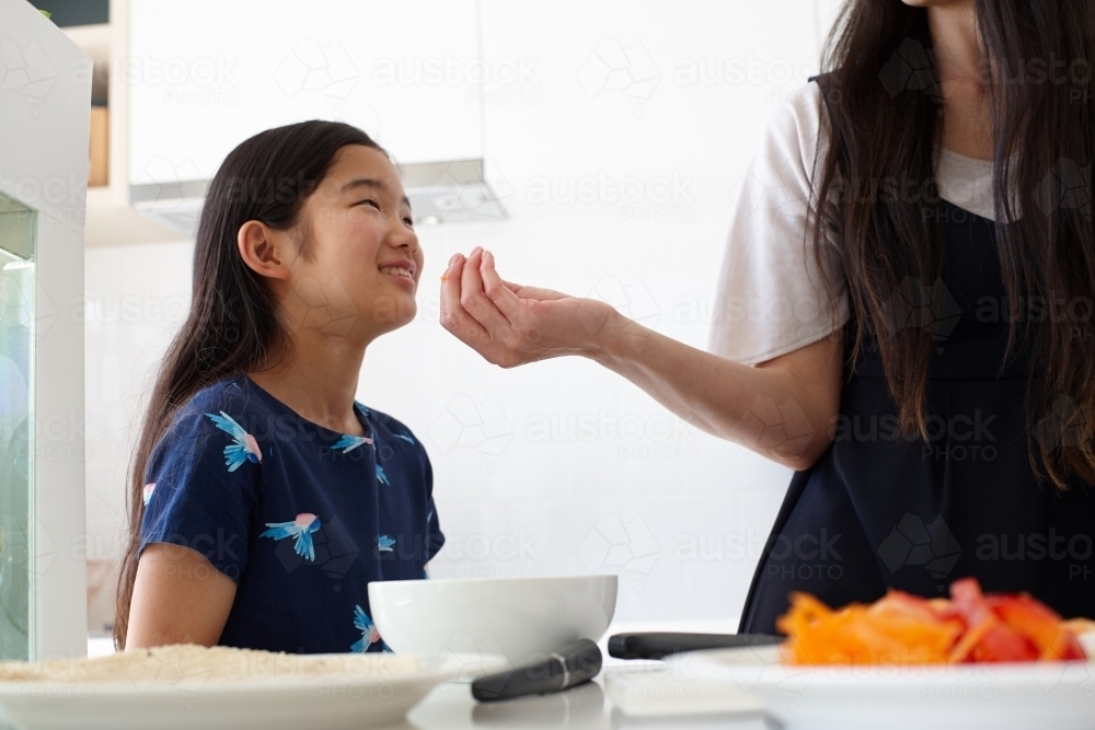 Mother and daughter in kitchen together preparing lunch - Australian Stock Image