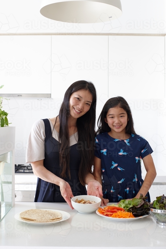 Mother and daughter in kitchen together preparing lunch - Australian Stock Image