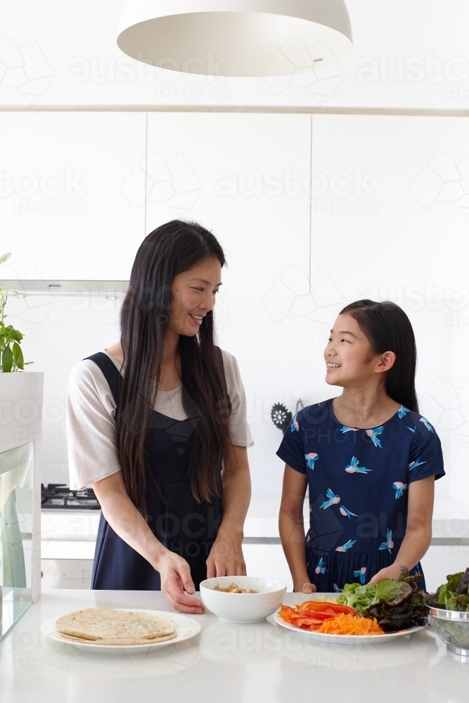 Mother and daughter in kitchen together preparing lunch - Australian Stock Image