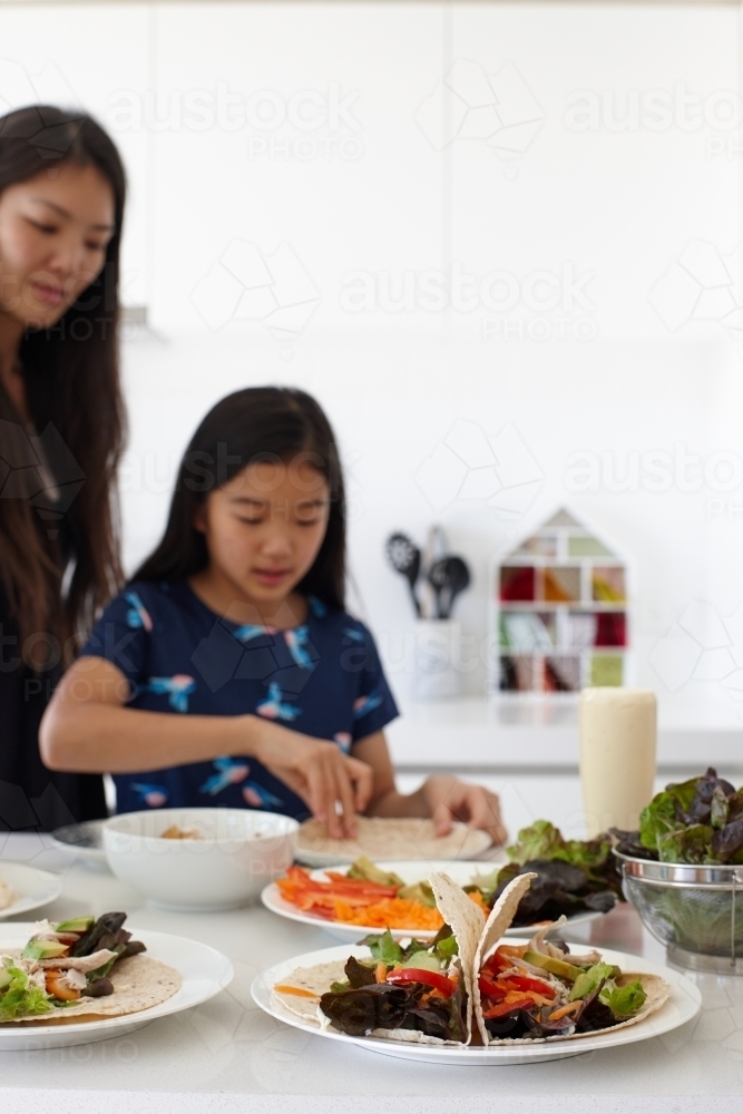 Mother and daughter in kitchen together preparing lunch - Australian Stock Image