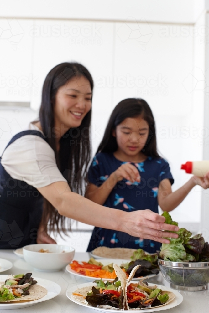 Mother and daughter in kitchen together preparing lunch - Australian Stock Image