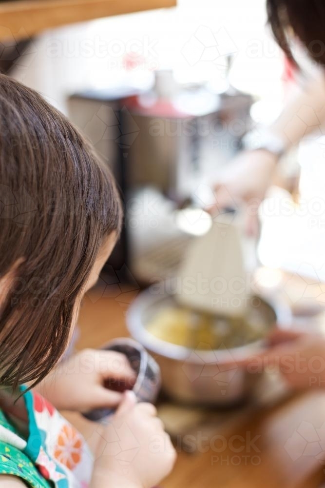 Mother and daughter making cake dough with an electric beater - Australian Stock Image