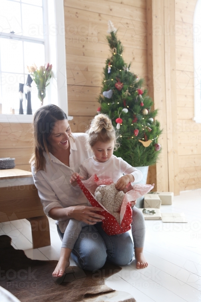 Mother and daughter opening present in front of Christmas tree - Australian Stock Image