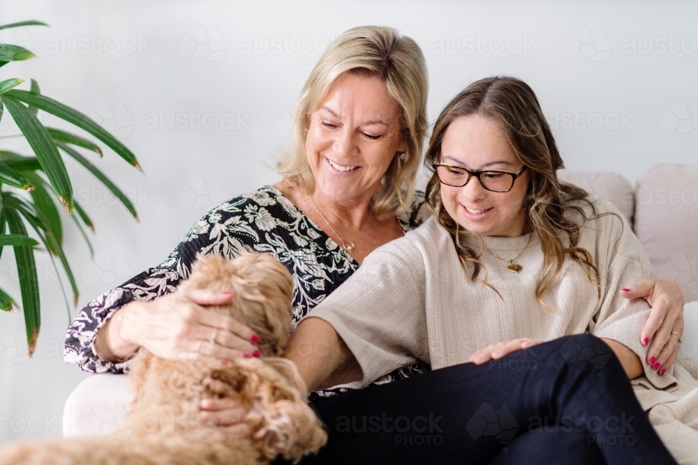 mother and daughter  patting their dog, from a series featuring a young woman with Down Syndrome - Australian Stock Image