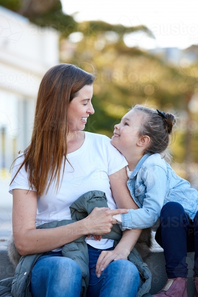 Mother and daughter sharing time laughing at beach promenade - Australian Stock Image