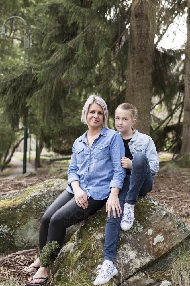 Mother and daughter sitting on a rock - Australian Stock Image