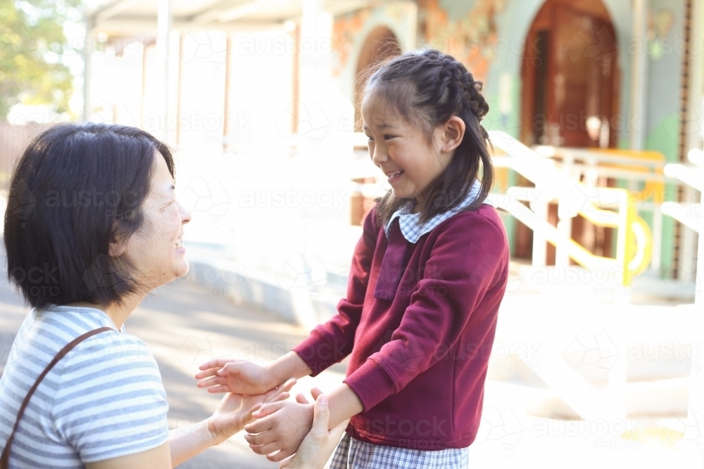 Mother and daughter smiling at talking together at school - Australian Stock Image