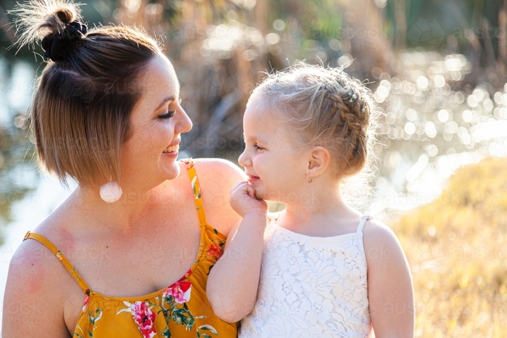 Mother and daughter smiling together outside - Australian Stock Image