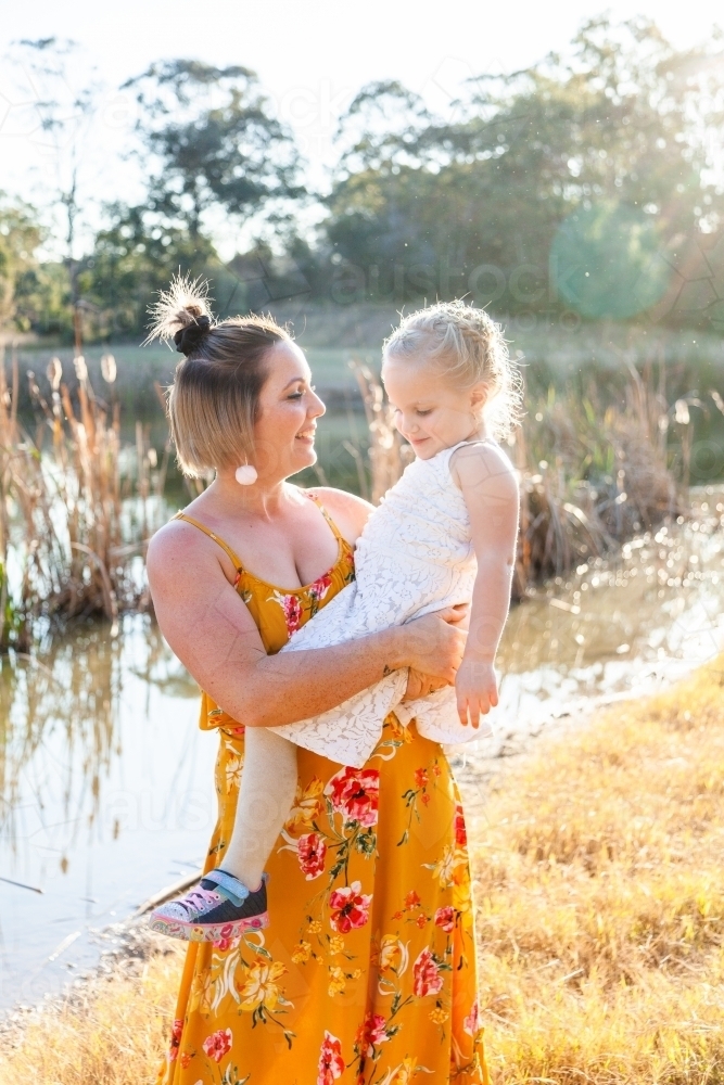 Mother and daughter smiling together outside - Australian Stock Image