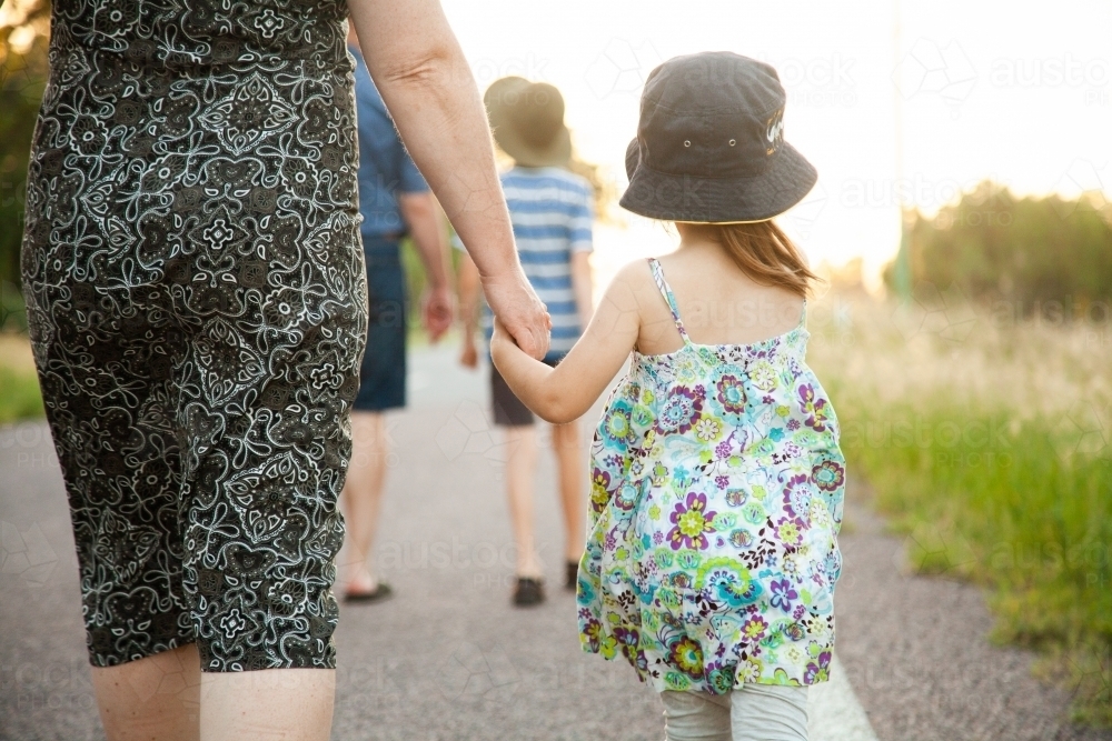Mother and daughter walking along a road holding hands - Australian Stock Image