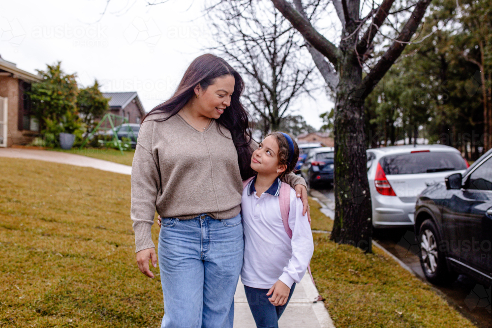 Mother and daughter walking on footpath on the way to school - Australian Stock Image