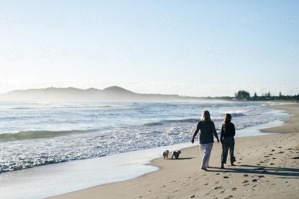 Mother and daughter walking on the beach with dogs - Australian Stock Image