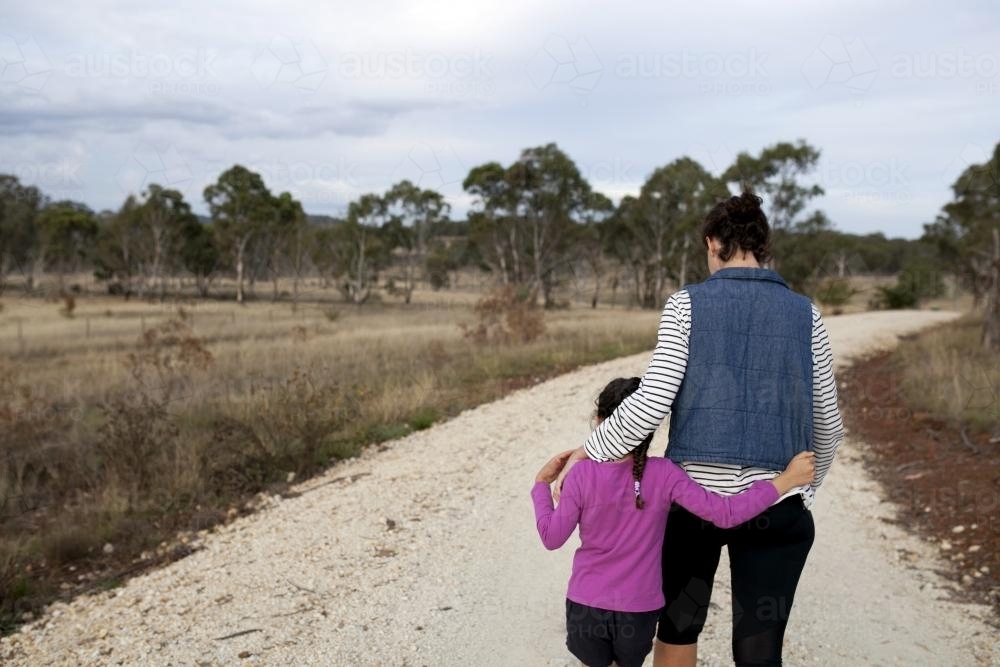 Mother and daughter walking together on unsealed country road - Australian Stock Image