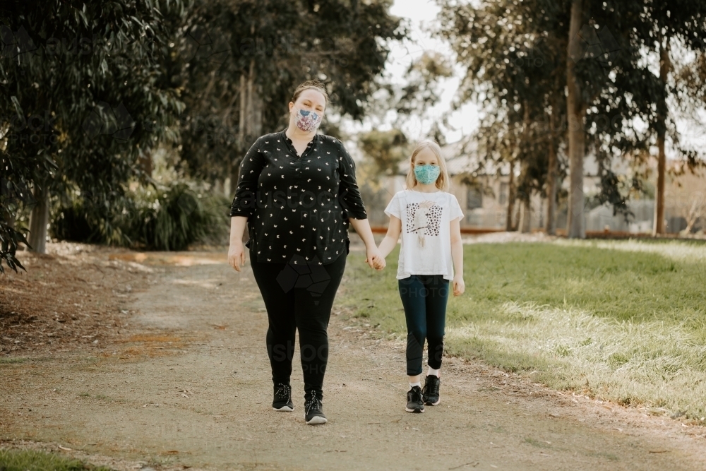 Mother and daughter wearing fabric masks during the corona virus COVID-19 pandemic going for a walk - Australian Stock Image