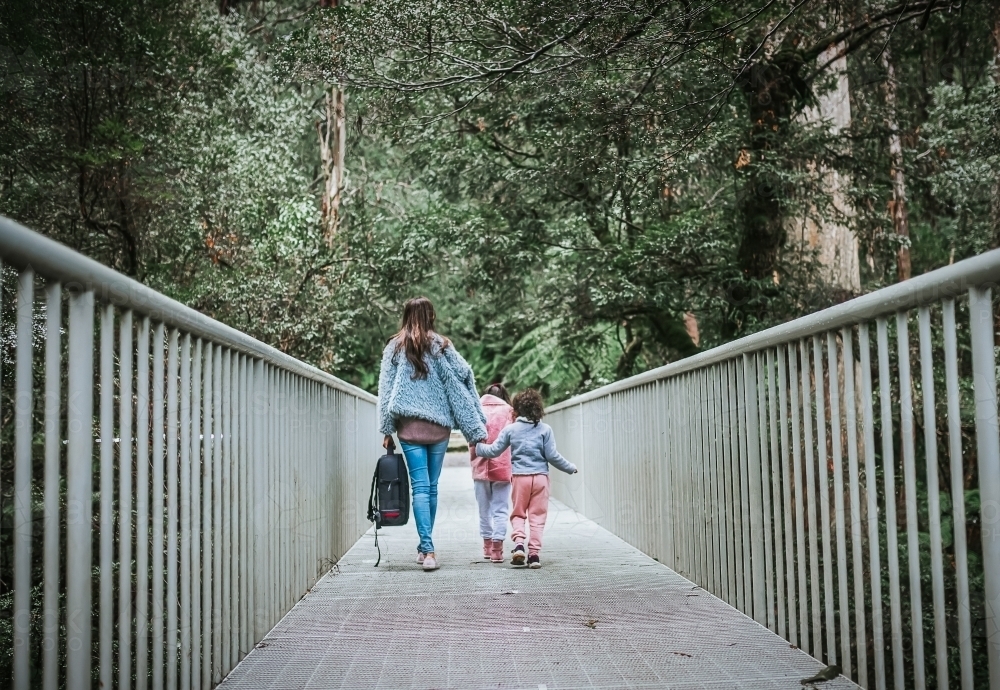 Mother and daughters walking on a bridge - Australian Stock Image
