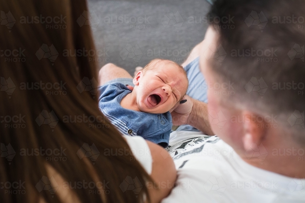 Mother and father holding crying baby boy - Australian Stock Image