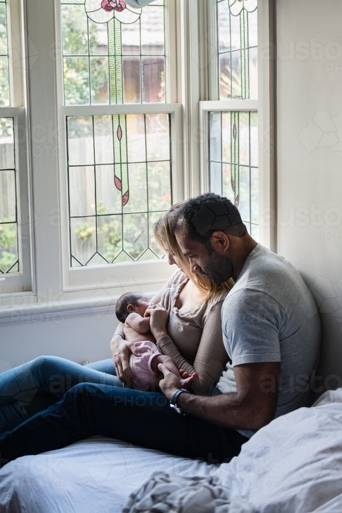 Mother and father with baby getting newborn cuddles - Australian Stock Image