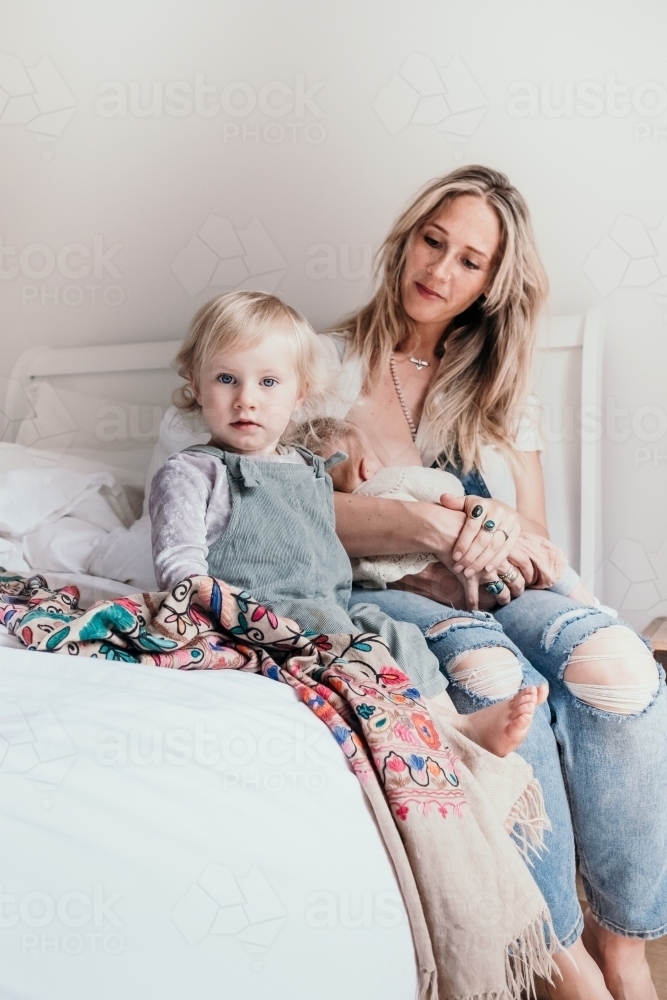 Mother and her two children sitting on the bed. - Australian Stock Image