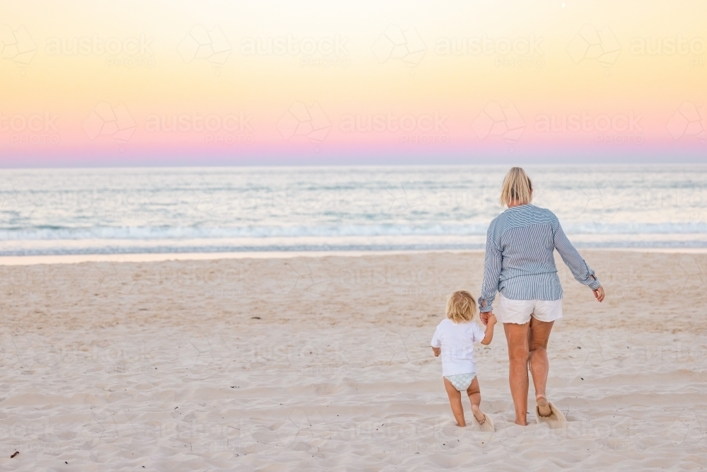 Mother and son holding hands walking on the beach on the Gold Coast, QLD Australia - Australian Stock Image