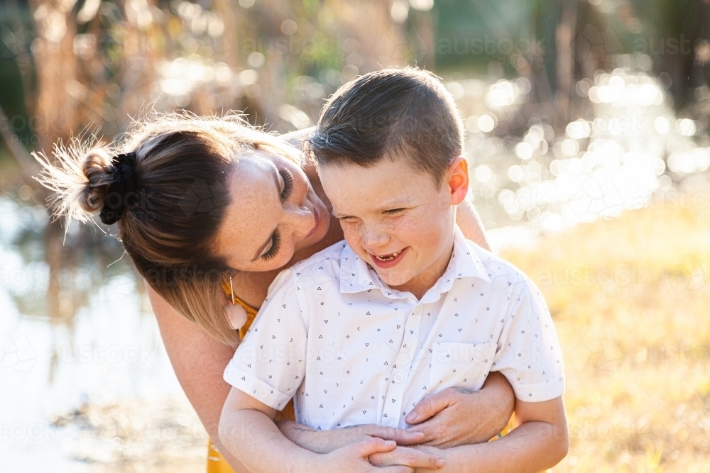Mother and son hug outside beside dam - Australian Stock Image