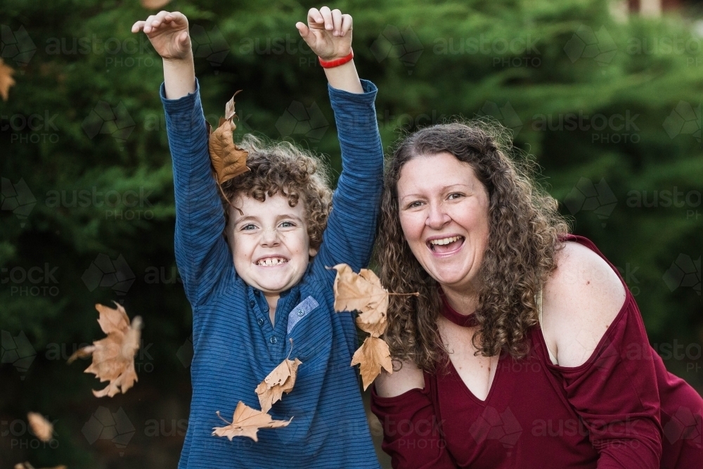 Mother and son playing in autumn leaves - Australian Stock Image