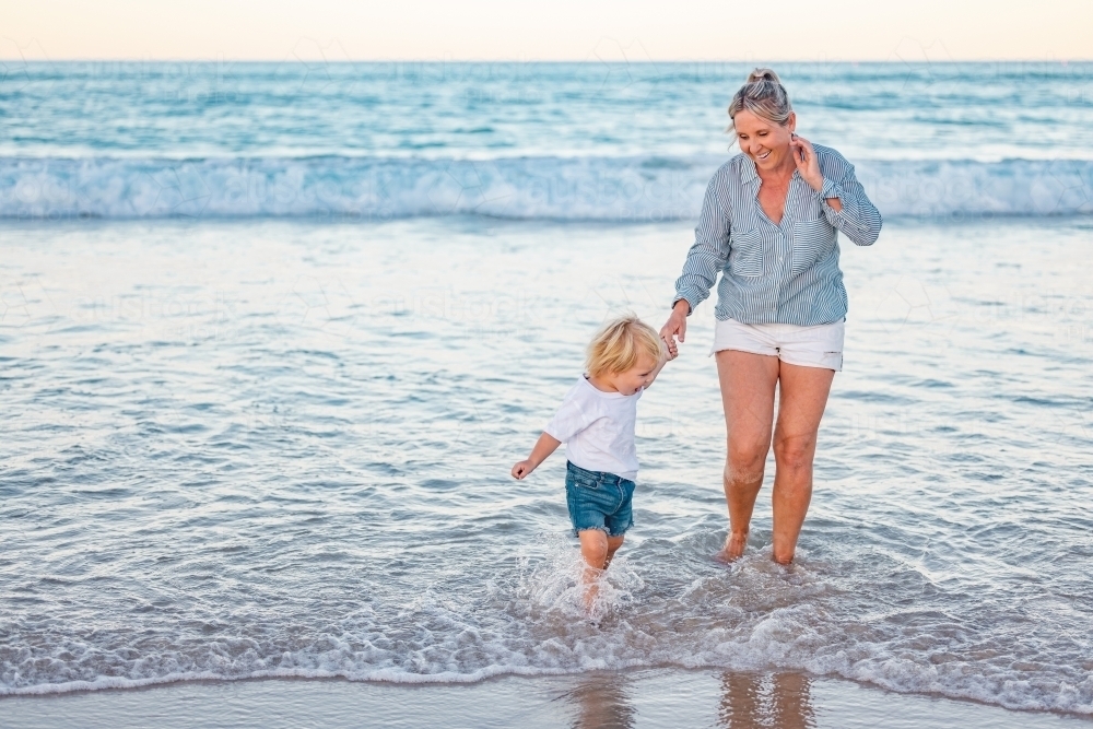 Mother and son playing in shallow water on Gold Coast beach - Australian Stock Image