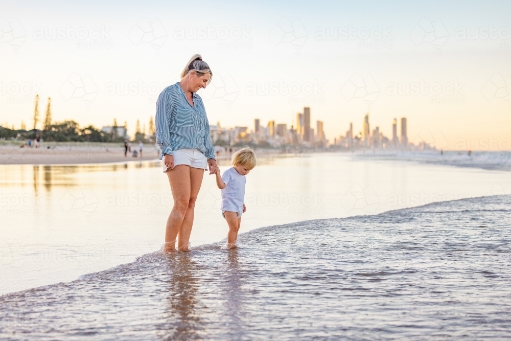 Mother and son playing in shallow water on Gold Coast beach - Australian Stock Image