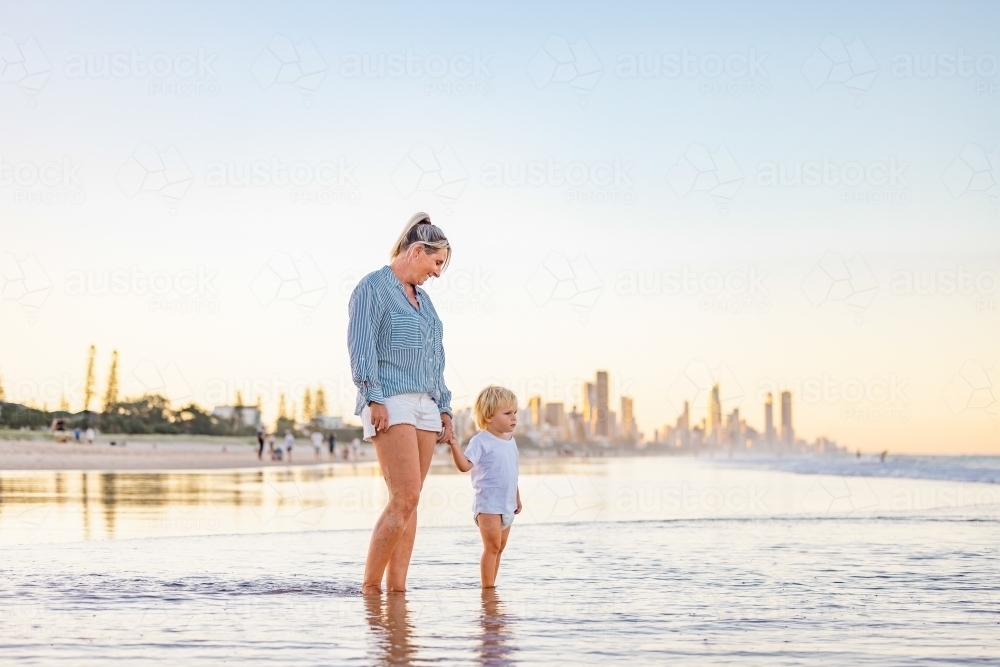 Mother and son playing in shallow water on Gold Coast beach - Australian Stock Image