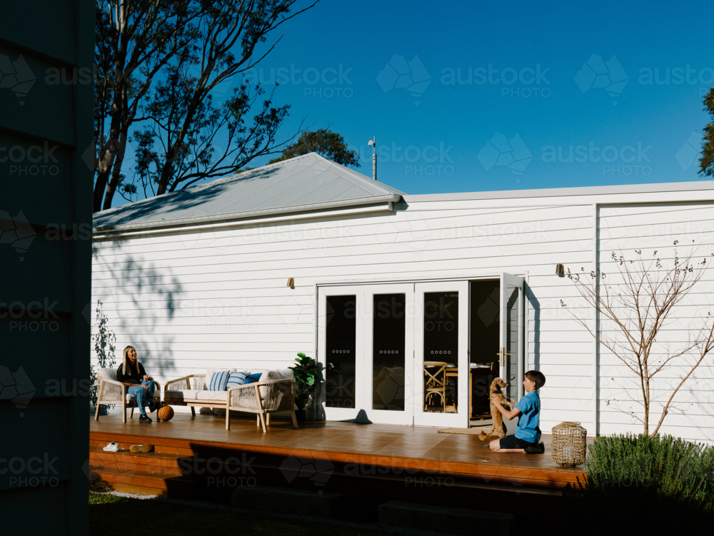 Mother and son spending time outside in the wooden deck. - Australian Stock Image