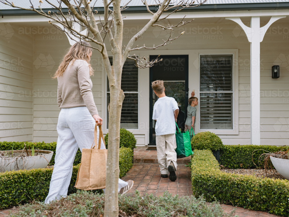 Mother and son walking on a brick pathway towards the house - Australian Stock Image