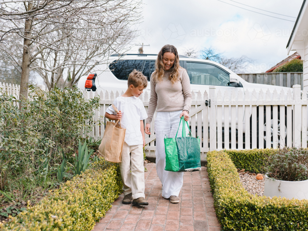 Mother and son walking on a brick pathway towards the house - Australian Stock Image