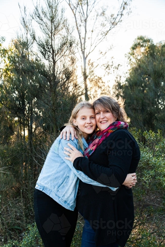 Mother and teen daughter embrace one another in hug - Australian Stock Image
