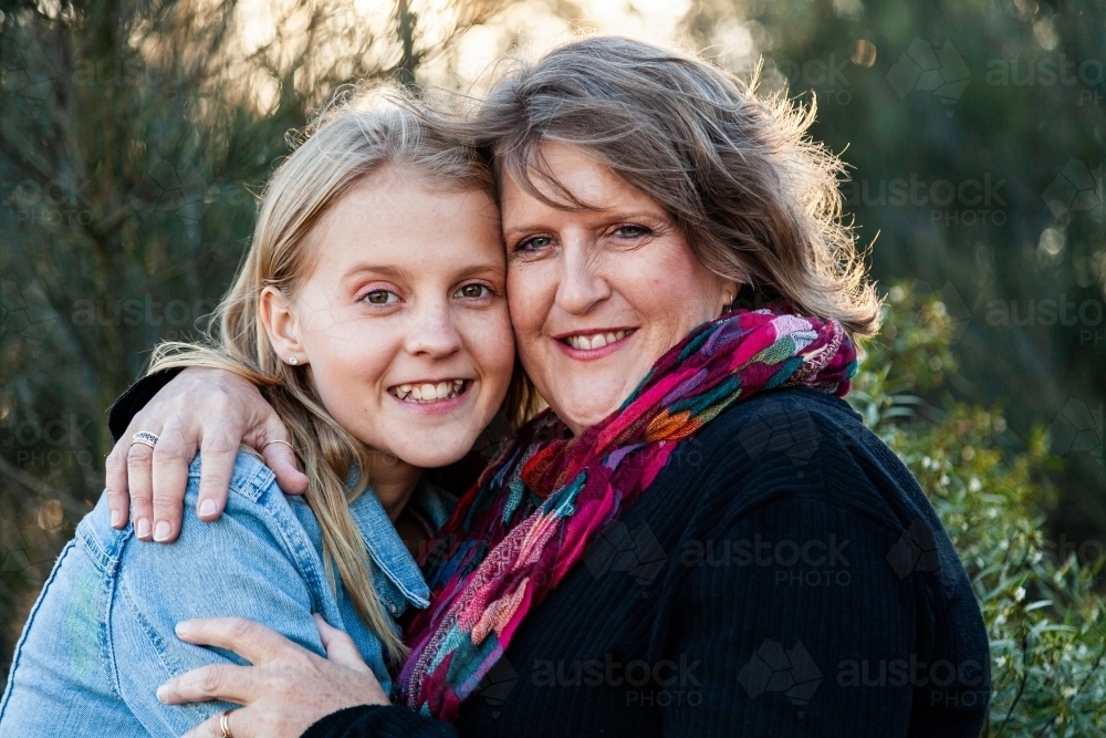 Mother and teen daughter embrace one another in hug - Australian Stock Image