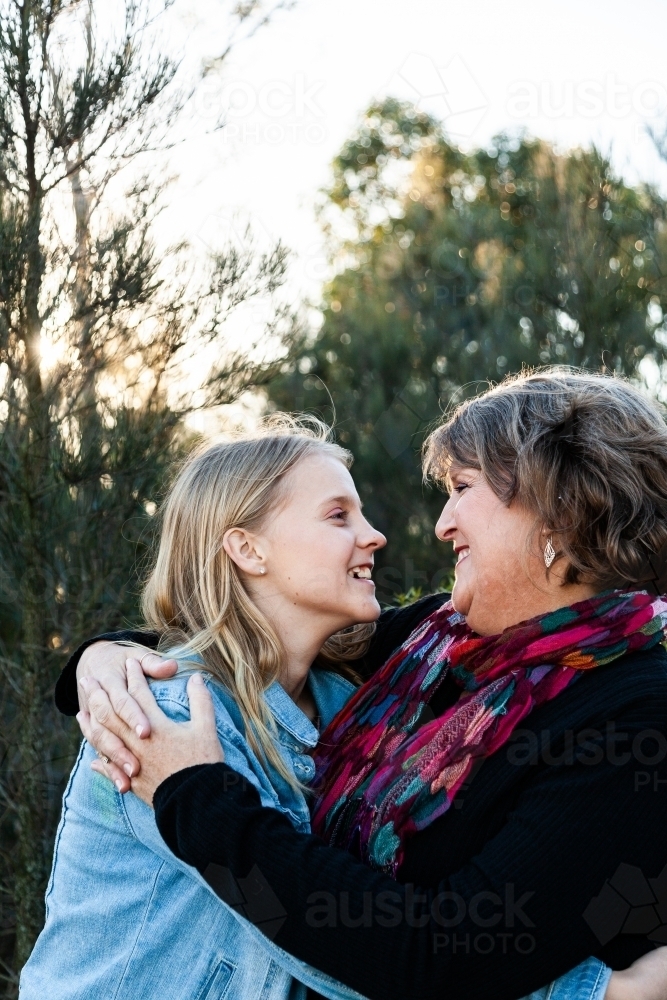 Mother and teen daughter embrace one another in hug - Australian Stock Image