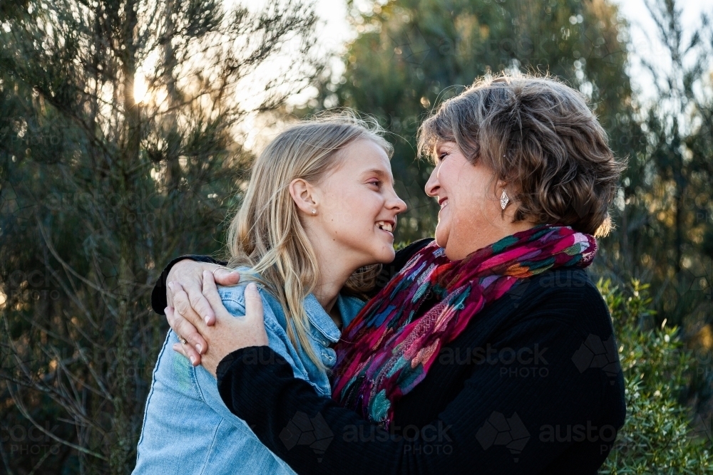 Mother and teenage daughter hug outside - Australian Stock Image