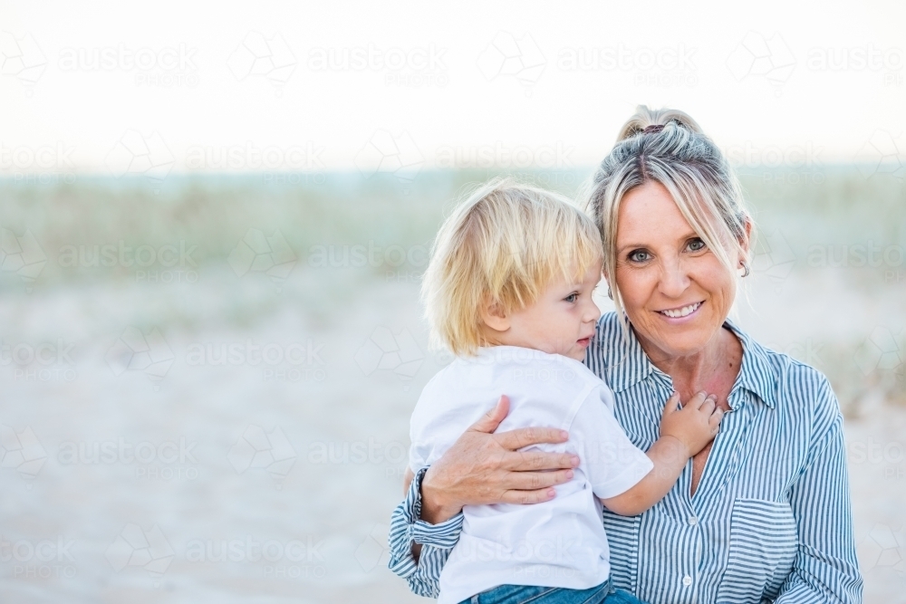 Mother and toddler son embracing on the sand of Gold Coast beach - Australian Stock Image