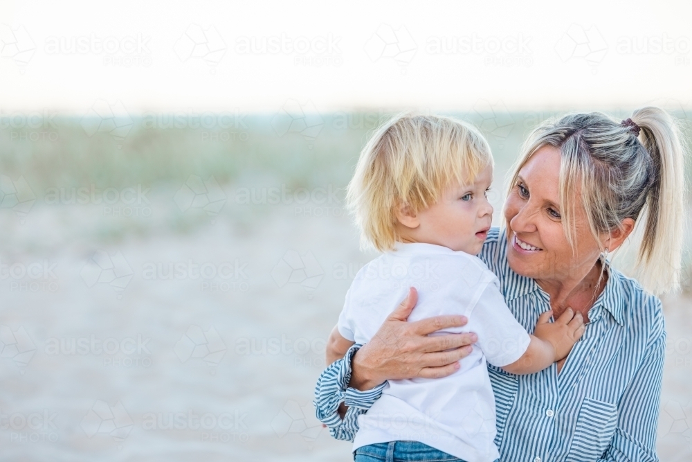 Mother and toddler son embracing on the sand of Gold Coast beach - Australian Stock Image